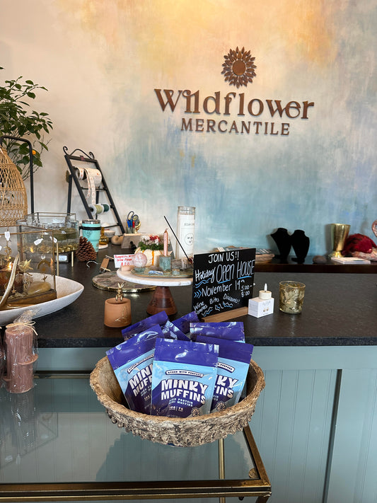 Wildflower Mercantile shop sign on the wall with a basket of Minky Muffins bags near the checkout counter