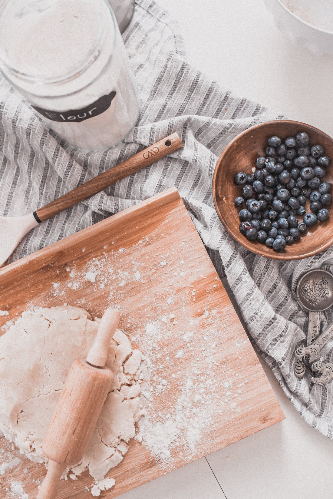 Dough, flour, and blueberries to be used for baking. Photo by Paige Cody on Unsplash